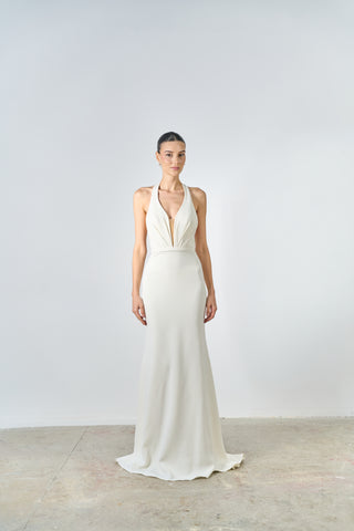 Woman wearing a white gown with a plunging neckline on a plain background