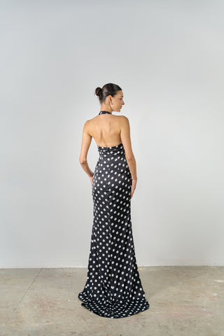 Woman wearing a black and white polka dot halter neck gown against a plain background