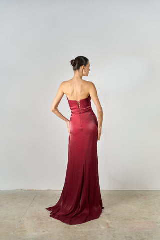Woman wearing a burgundy evening gown against a plain background
