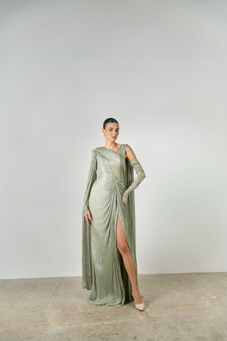 Woman wearing a long, elegant green dress with a slit on a plain background