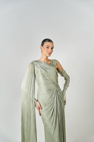 Woman wearing a light green draped dress against a plain background