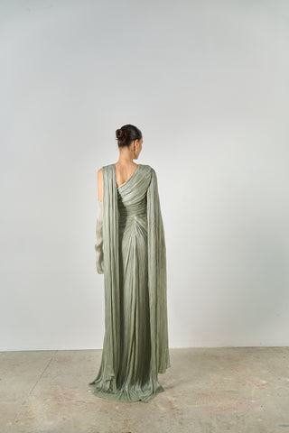 Woman wearing a green evening gown with a draped design on a plain background