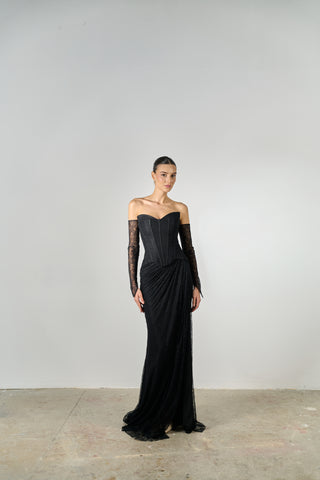 Woman wearing a black evening gown with long sleeves against a plain background