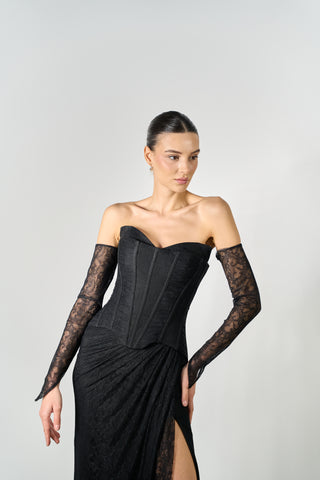 Woman wearing a black strapless gown with lace sleeves on a gray background