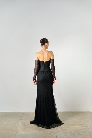 Black evening gown with sheer sleeves on a plain background