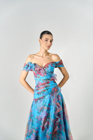 Woman wearing a colorful off-shoulder dress against a plain background
