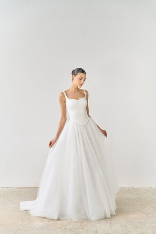 Woman wearing a white wedding dress against a plain background
