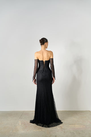 Black evening gown with sheer sleeves on a plain background
