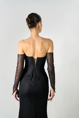 Woman wearing a black dress with lace sleeves on a plain background