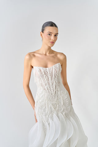 Woman wearing a white strapless dress against a plain background