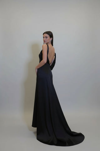 Woman wearing a black evening gown with a plunging neckline on a plain background