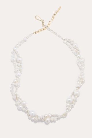 Statement necklace with organic pearl arrangement and contemporary fluid form, embodying artisanal craftsmanship and timeless sophistication.