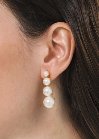 Pearl earring worn by a person with dark hair.