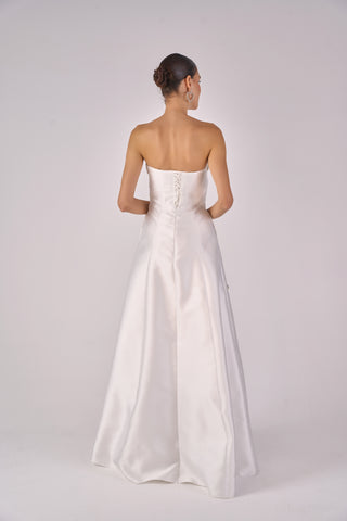 Woman wearing a strapless white gown on a plain background