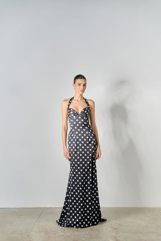 Woman wearing a black dress with white polka dots against a plain background