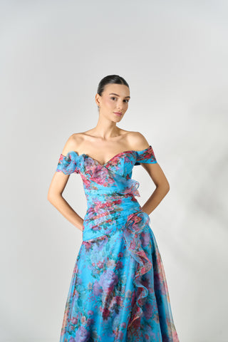 Woman wearing a blue floral off-shoulder dress against a gray background