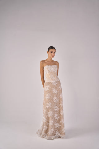 Woman wearing a strapless lace dress on a plain background