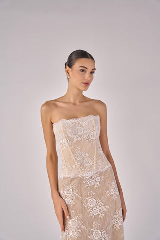 Woman wearing a strapless lace dress against a plain background