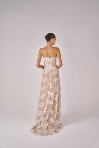 Woman wearing a strapless lace gown on a white background