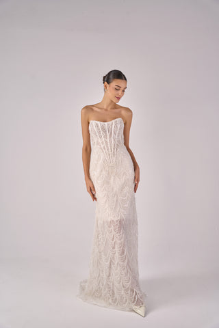 Woman wearing a strapless lace wedding dress on a plain background