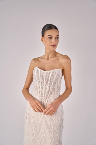 Woman wearing a strapless lace wedding dress against a plain background