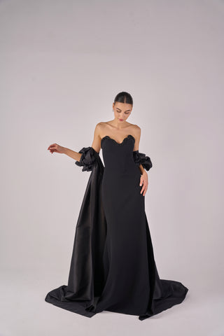 Woman wearing a black evening gown with floral details on a white background