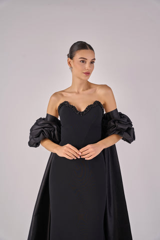 Woman wearing a black dress with puffed sleeves on a gray background