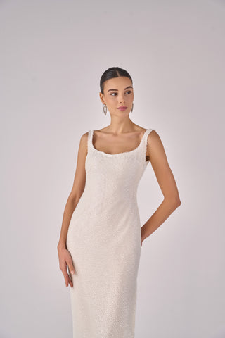 Woman wearing a white sleeveless dress against a plain background