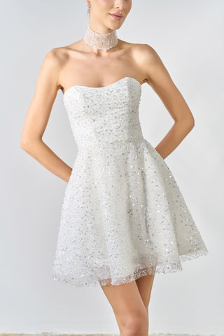 Woman wearing a strapless white lace dress against a plain background