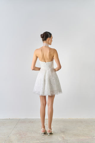 Woman wearing a white lace dress with a plain background