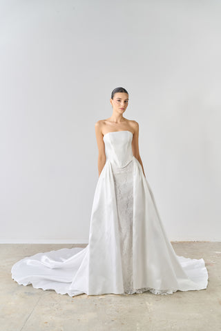 White strapless wedding dress with a long train on a plain background