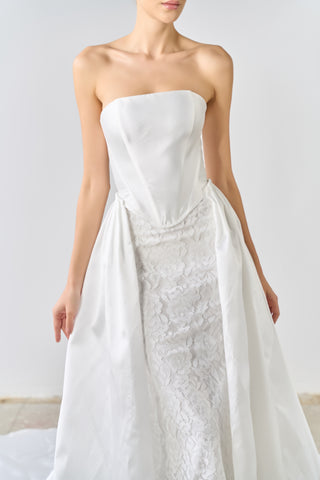 White strapless wedding dress with lace detailing on a plain background