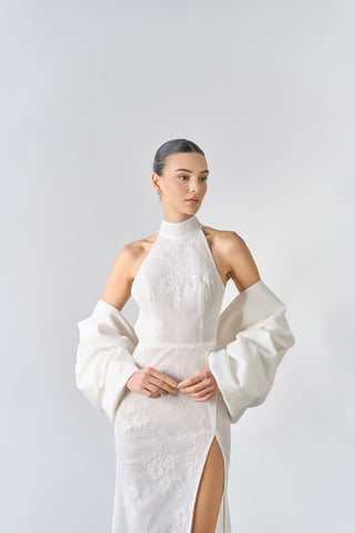 Woman wearing a white dress with long sleeves against a plain background