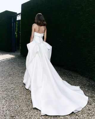 Luxurious mikado bridal gown showcasing a minimalist front design and couture-crafted bustle drape with a regal train.