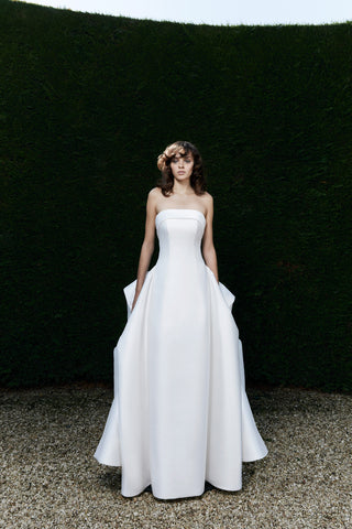 Couture strapless wedding dress with bold graphic details, structured column fit, and a dramatic flowing train.