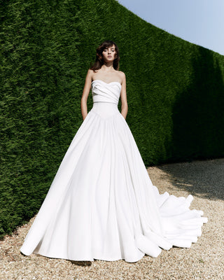 Luxury A-line wedding dress with a draped sweetheart neckline, structured silhouette, and a dramatic circular train.