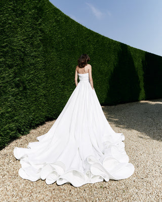 Sophisticated bridal gown featuring a low basque waistline, voluminous skirt, and couture-inspired circular train.