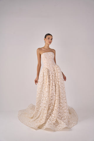 Model wearing a strapless lace wedding gown on a white background