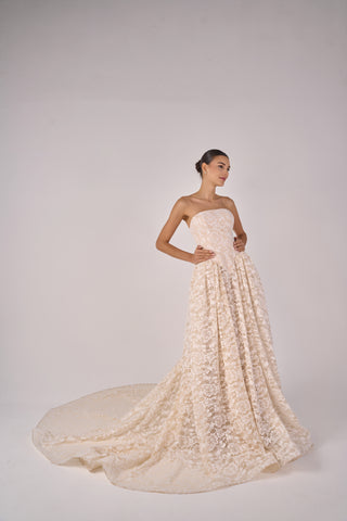 Woman wearing a strapless lace wedding gown on a plain background