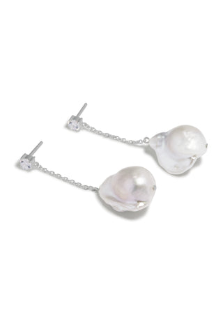Asymmetric designer earrings featuring organic baroque pearls suspended from delicate silver chains, finished with a sparkling cubic zirconia accent.