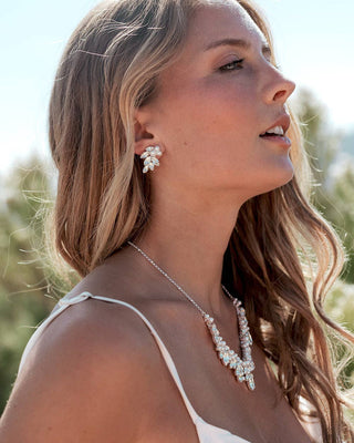 Woman wearing a necklace and earrings with a blurred natural background
