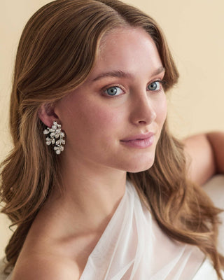 Woman wearing a pair of earrings with a neutral background