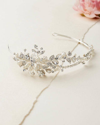 Silver tiara with floral and crystal details on a light background