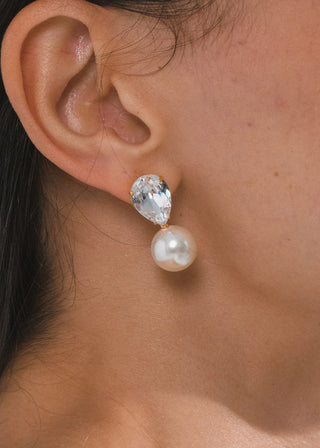 Close-up of an ear wearing a pearl and crystal earring.