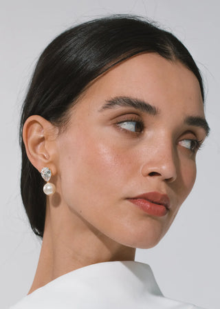 Close-up of a woman wearing earrings with a plain background