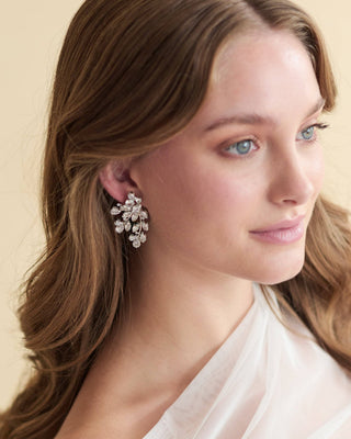 Woman wearing a pair of earrings with a neutral background