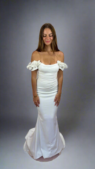 Woman wearing a white off-shoulder dress against a gray background