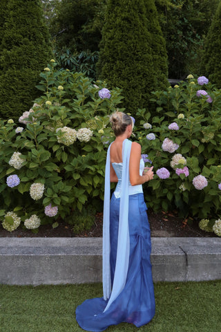 Luxurious strapless column gown with flowing cape detail and floor-length satin finish for formal evening elegance