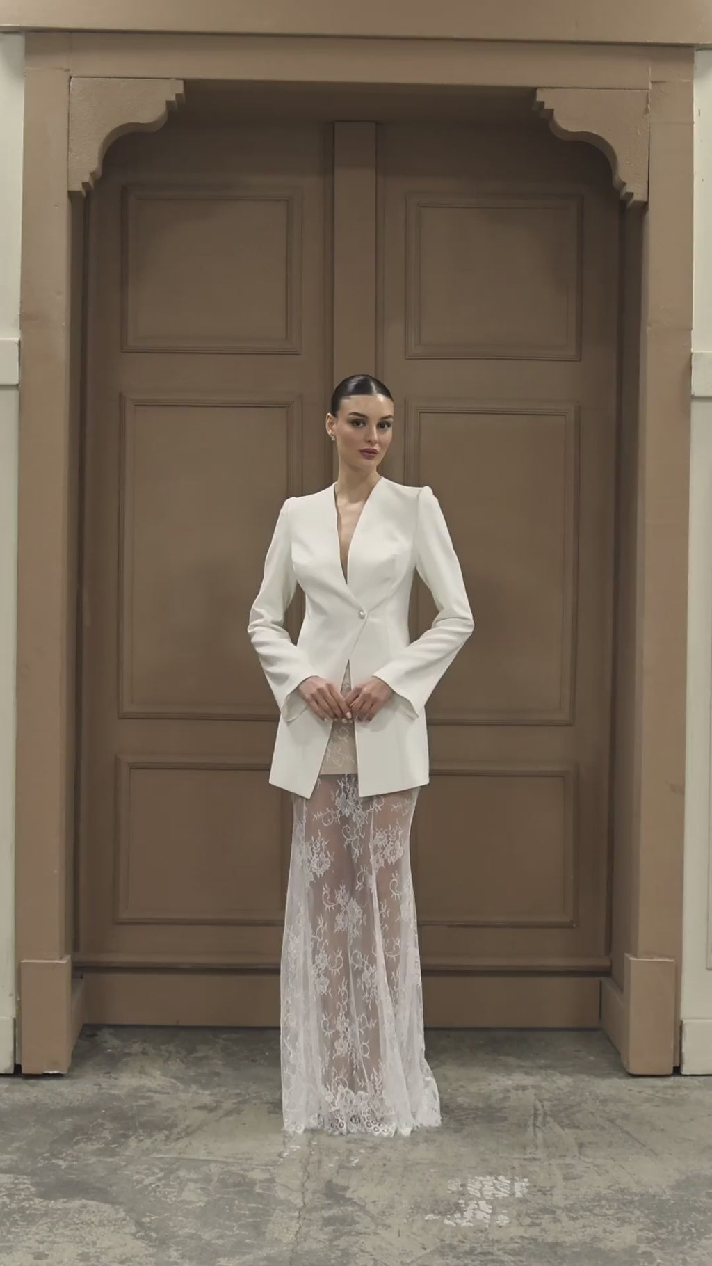 Modern bridal gown with a striking V-neck blazer bodice and flowing lace skirt, perfect for contemporary luxury weddings.