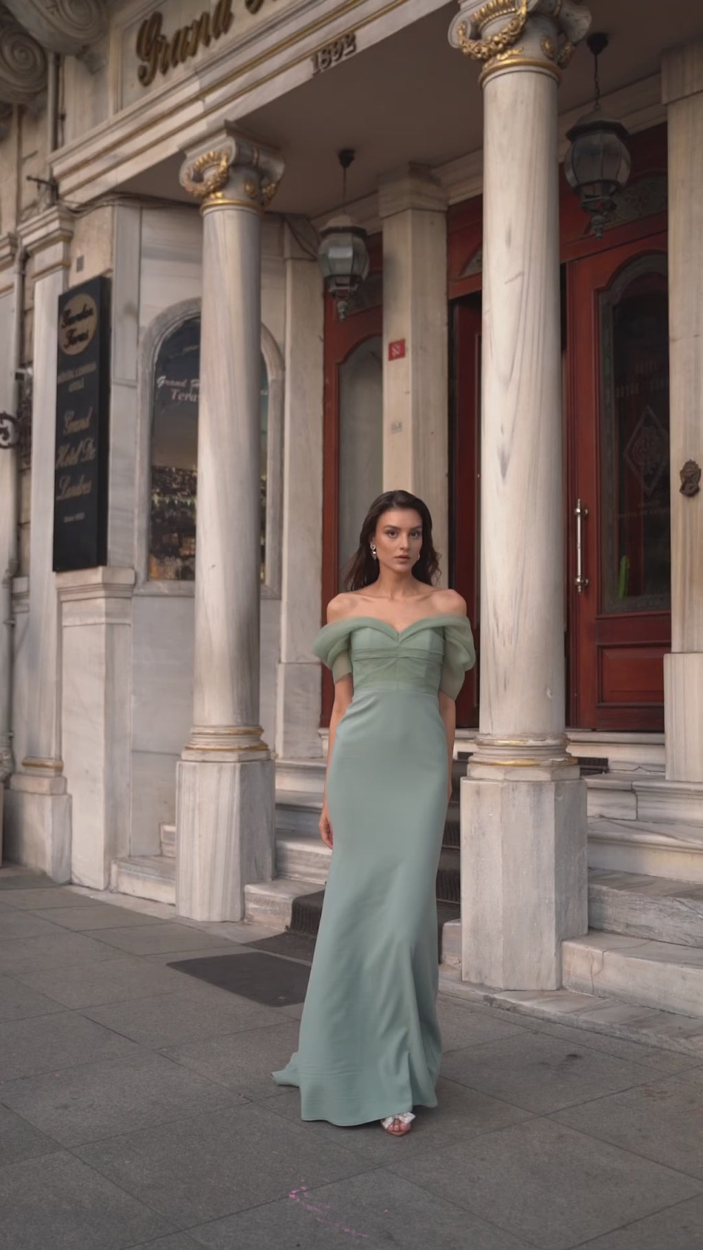 Video of the Diana Silk Organza and Crepe Gown by Nadia's in sage, highlighting the graceful drape of the crepe skirt and subtle train as the model moves.